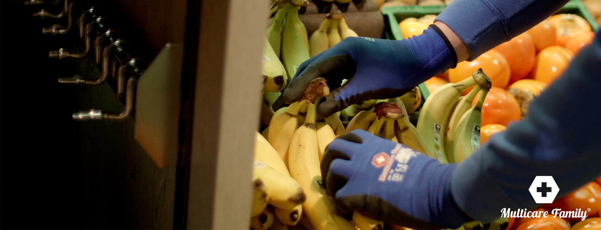 Behandschuhte Hände sortieren Bananen in der Obstabteilung.